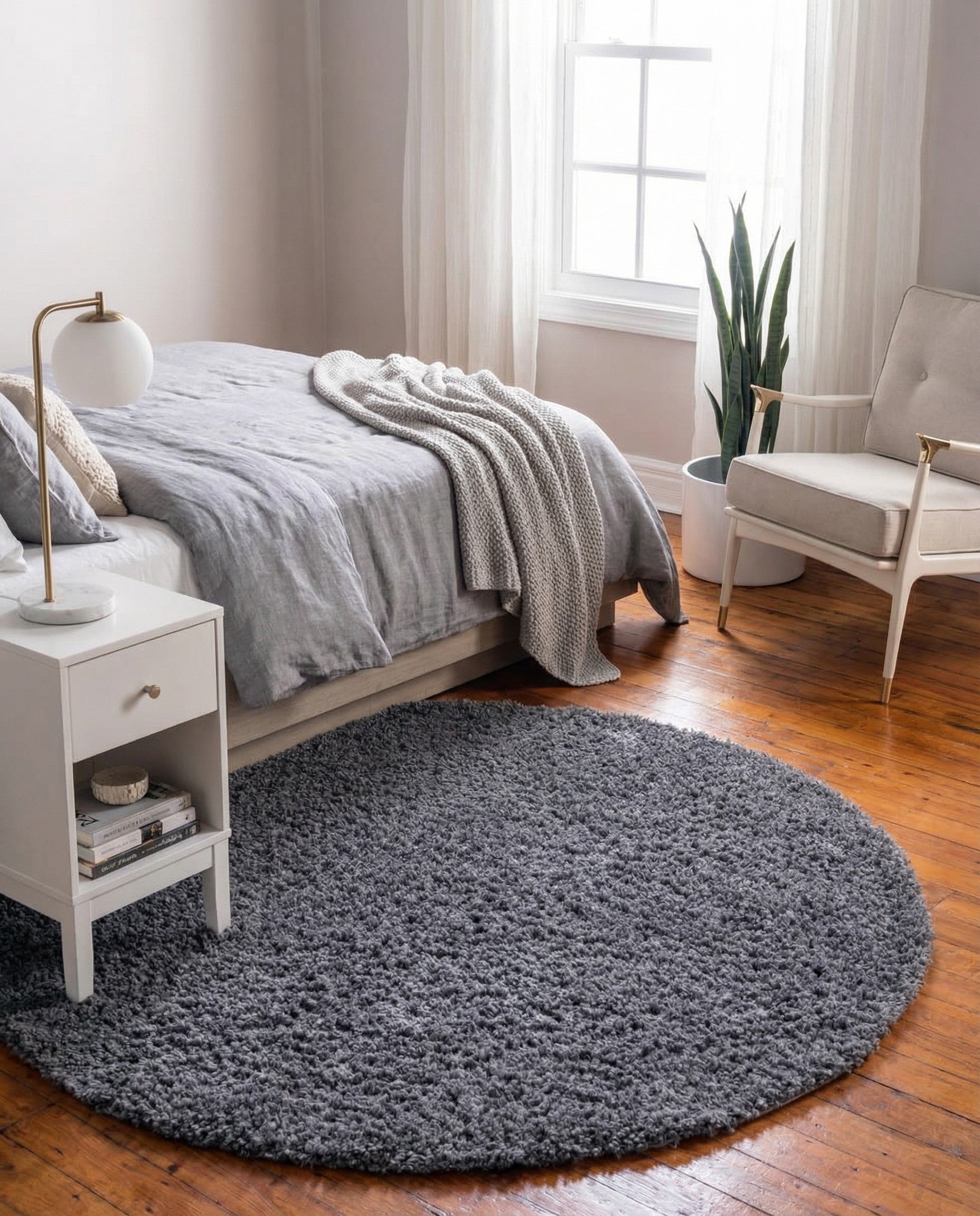 A soft, round 2' x 2' gray shag rug, made from polypropylene, offering a plush texture.