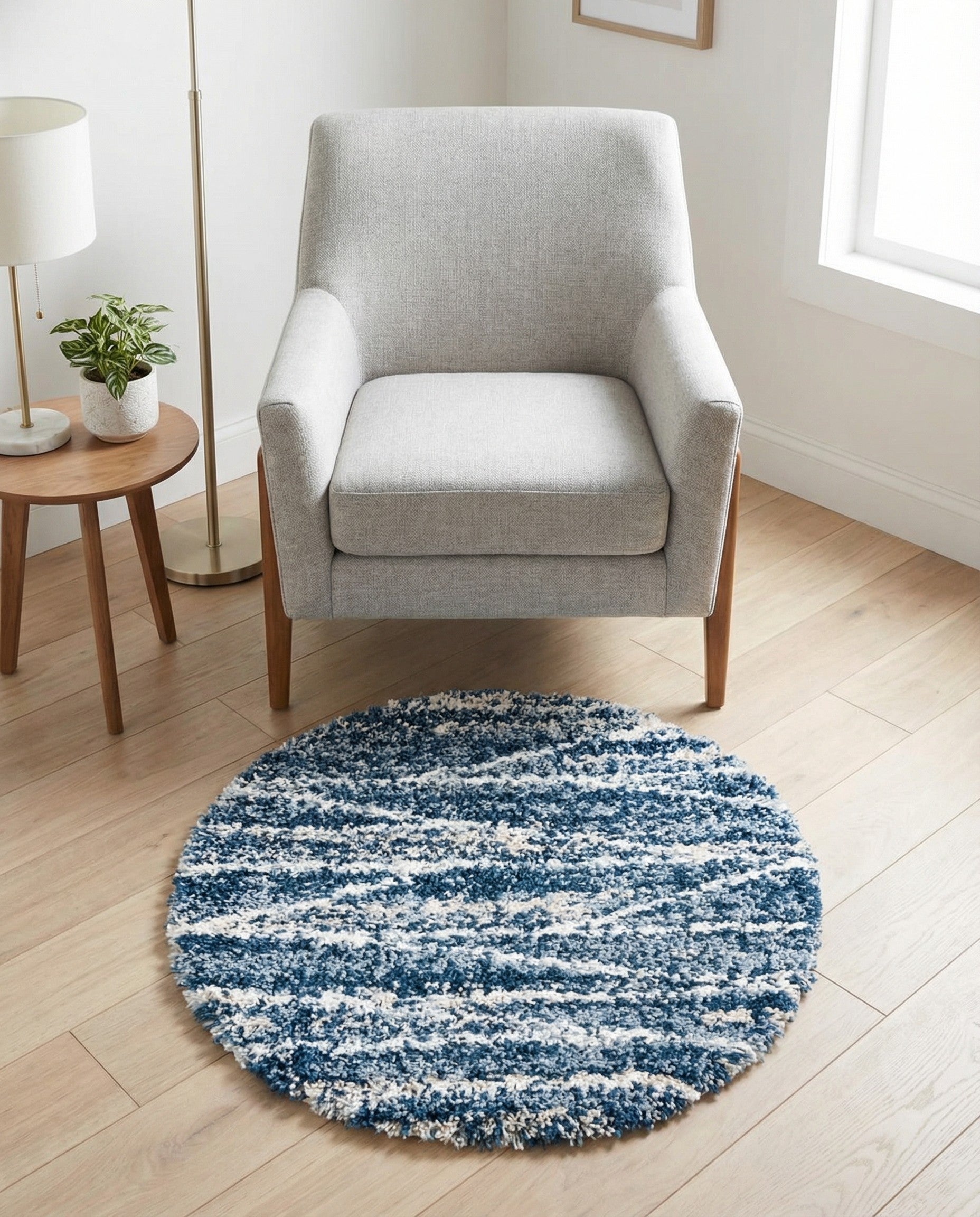 A round blue shag rug with a modern striped pattern in varying shades of blue, white, and light gray.